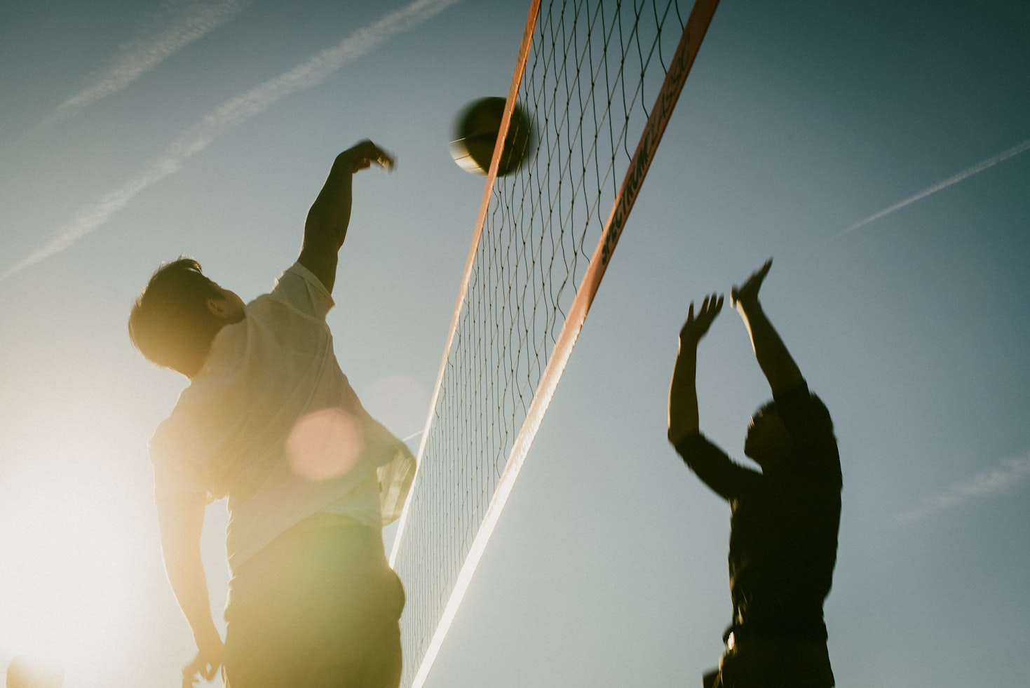 Friends playing beach volleyball at sunset